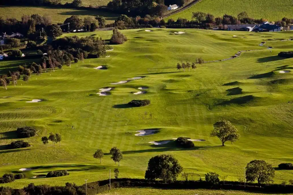 Aerial view of a green golf course with fairways and bunkers
