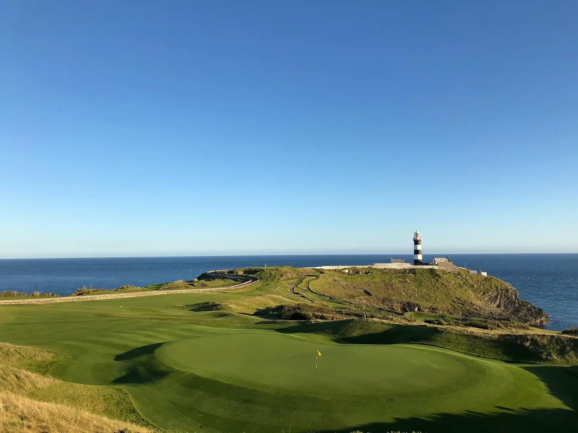 Coastal golf green beside the sea and a lighthouse